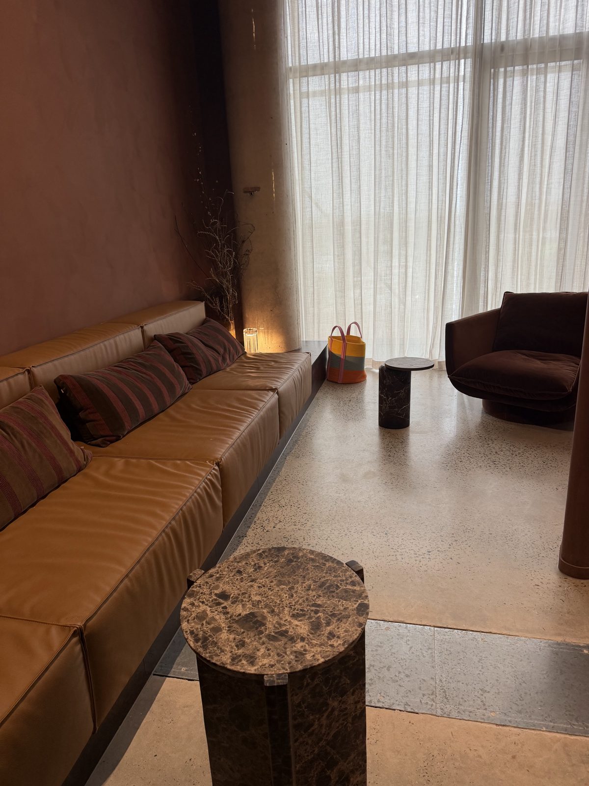 Waiting area with a long leather bench, striped cushions and sheer linen curtains